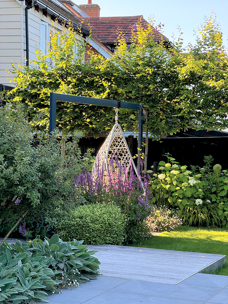 The box section frame for the hanging seat was powder-coated to match details on the house and the frame dropped into the ground, below the finished level, so none of the fixings are visible.