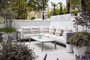 This luxurious space is the place for afternoon drinks and is located on the sunny upper level of a split level London garden. Planting is evergreen with colourful flowering in white-washed terracotta planters.