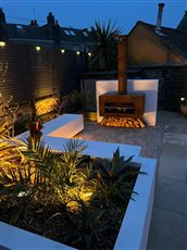 Garden Designed by Claire Winchester Garden Design Brighton
Lighting supplied and installed by Garden Spark 
Small contemporary garden with white walls and log burning patio heater with beautiful gentle garden lighting