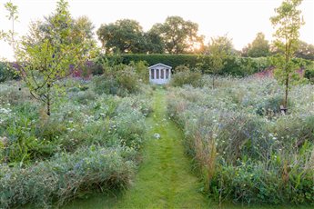 A Cheshire Garden. Sweeping paths take the garden visitor on a romantic journey through the swathes of wildflower meadow, planted with fruit trees. A hidden summerhouse provides a private place to sit and contemplate life.