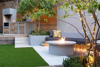 Richmond: Old meets new in contemporary development. Historic brick boundary wall serves as a backdrop to contemporary family garden that includes dining area, floating bench, firepit, bespoke kitchen and storage.