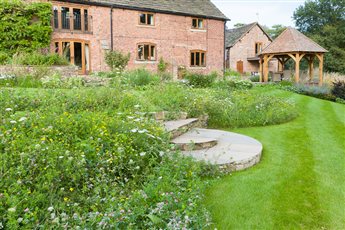 A Traditional Garden in Woodford. A meadow of wildflowers has been used to create a more naturalistic feel to this garden that overlooks a small woodland area.