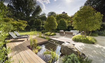 Decking wraps around the pond in 'Down to the River' in Hertfordshire. The decorative 'ripples' grid is a safety element for children whilst the pond is a wildlife haven.