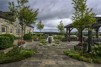 Farmhouse on Ilkley moor.  Contemporary country garden.  Large bespoke oak pergola, reclaimed yorkstone paved courtyard with waterfeature.  Stone circle firepit.