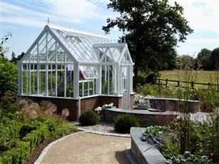 Glass house with paddlestone dry stone effect raised beds and seating