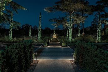 A formal garden view using layered low-glare lighting to create depth, rhythm and a clear after-dark focal point.