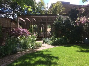 Rear garden view to custom pergola and dining area with mirror, pendant light and electric wall-fixed heater