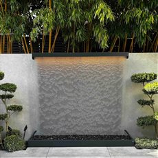 AquaVeil water wall set within a Japanese-inspired garden, framed by sculptural topiary and bamboo with a patio in front. The flowing water adds gentle movement and sound while complementing the surrounding planting.