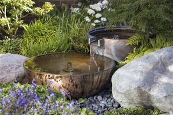 A double bowl copper water feature nestled amongst planting. It provides a focal point for the small courtyard and the sound softens the local traffic noise.