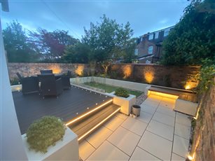 This garden is sleek and contemporary , the upper level being composite decking and the lower level pale cream porcelain. 