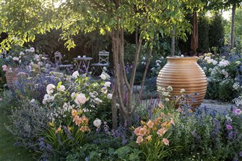 A ribbed terracotta water feature brings shimmer in this English Cottage Garden at the RHS Hampton Court Flower Show 'Best of Both Worlds' Garden 2018. This garden, full of scented roses and perennials, won a Gold Medal.