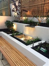 The back wall of this London garden featured cedar wood slatted screen and a stainless steel waterfeature which did the job of screening off the traffic noise.
