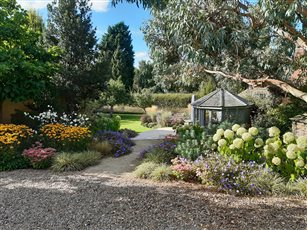 A West Yorkshire country garden. Colourful planting was used to provide a visual connection between the clients' farmhouse and the garden beyond, with glimpses of the lawn, seating area and summer house. 