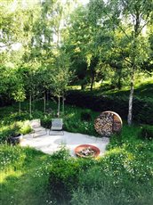 nature's doing its best in this garden, a bee and butterfly nectar pot with a simple layout of grey sawn sandstone, quartz paddlestones all knitted together with meadow mix and bold clipped yew buttresses and buxus balls