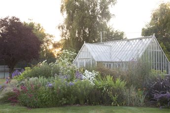 A richly planted border frames this stunning Victorian greenhouse in a wildlife friendly garden in Sussex. 
Photo Credit: Abigail Rex