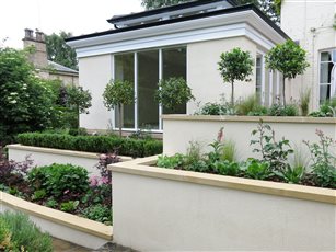 Terraced planting beds help the transition between the upper level of this garden, and the lawn below. The walls have been rendered to coordinate perfectly with the new Orangery.