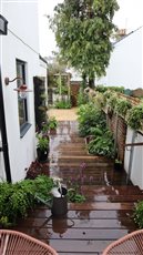 A narrow side return of a house transformed with a hardwood deck, trellis above the existing brick walls for privacy, with pots, climbers and shade tolerant planting. 