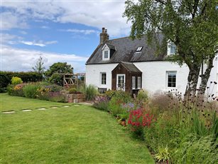 Highland cottage garden near Tain, enclosed by a native hornbeam hedge to create a sheltered sanctuary. Generous, layered perennials and shrub roses sit alongside sandstone raised planters, a timber pergola and a productive kitchen garden.
