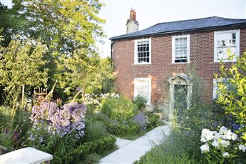 Formal front garden for a Georgian farmhouse in Kent. Quartered paths with romantic rose and perennial parterre beds edged with a low hedge. Pleached crab apple trees and estate metal fence. 
Photo Credit: Annaick Guitteny 