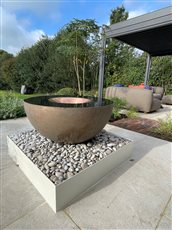 The Specular water feature with aged bronze inner flute and bowl. Shown with powder coated side panels for the reservoir cladding.