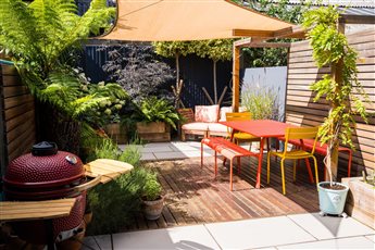 A Courtyard vibe saw a grey porcelain tile patio coupled with a hardwood deck fill the surface. A pergola installed to give privacy along with a raised bed constructed from treated softwood railway sleepers. 