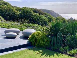 Coastal planting and polished concrete pebble seats grace the terrace in this Cornish coastal garden