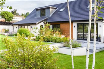 A family garden in Prestbury with a large water feature that divides the main terrace into dining and seating areas. Raised planting beds form a retaining wall to hold back the lawn at a higher level.