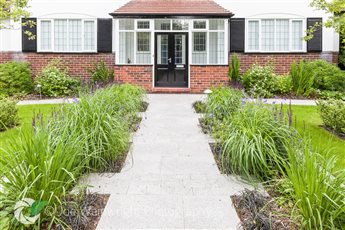 A new path was installed in the front garden of a house in Heaton Mersey, creating a symmetrical garden design using two lawns and large borders.