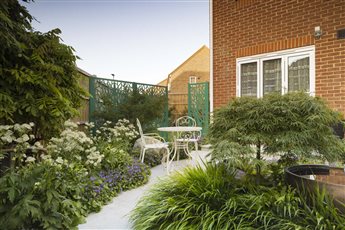 In 'The Tranquil Garden' laser cut screens provide a division between garden space and add an element of privacy in an Urban garden. The Japanese maple frames the copper water feature.