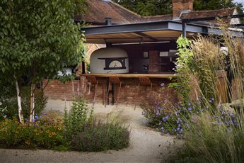 Hestia Garden at The Plough Shiplake in Oxfordshire; view of the bespoke outdoor chef's kitchen, producing food cooked over woodsmoke for the garden diners. Photograph Alister Thorpe.