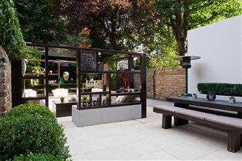 The garden in Maida Vale, West London is on two levels with the main area adjoining the house containing two separate areas for dining and for entertaining and relaxation. Flooring throughout is large rectangular cream travertine paving.