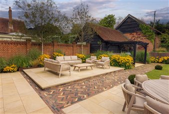 Relaxed seating with contrasting herringbone paths to delineate zones in this restored stableyard garden.