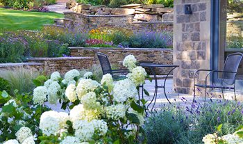 A new garden for a country villa near Sheffield. The sloping site had been excavated to enable the house to be extended. Retaining walls were built using stone from the excavations to create a series of planted terraces with patio and water feature.