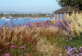 Abundant planting in a garden fronting a tidal estuary.