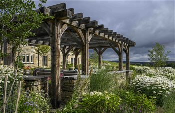 Rural garden design for a Yorkshire farmhouse on Ilkley Moor incorporating a stone Firepit circle, large bespoke oak pergola and Yorkstone paving. 