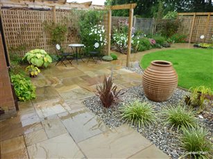 Simple patio area with privacy screens and path access to hidden veg area.