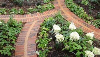Decorative and practical brick path fan detail divides woodland planting in a stylish front garden.
