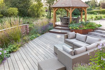 A Traditional Garden in Woodford. A new seating area and dining area was created with beautiful wooden decking, complimented by a stunning cedar gazebo that provides shade on a sunny day. 
