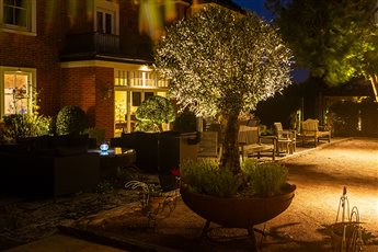 Garden lighting design and installation by Mark Packham, Garden and Landscape Lighting Designer at Garden Spark 
Country house with boule court and olive in corten planter gently illuminated at night