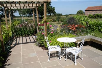 Cottage garden in North Yorkshire with a simple seating area and pergola.