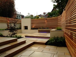 A courtyard garden in Alderley Edge has been given a contemporary style. Pale stone paving brings light to a dark area, with a bespoke inbuilt stone bench providing permanent seating in a small space. A feature wall creates the main focal point.