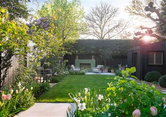 Joanna Archer Garden Design London garden with black painted fence, pleached trees for privacy and gas fireplace.